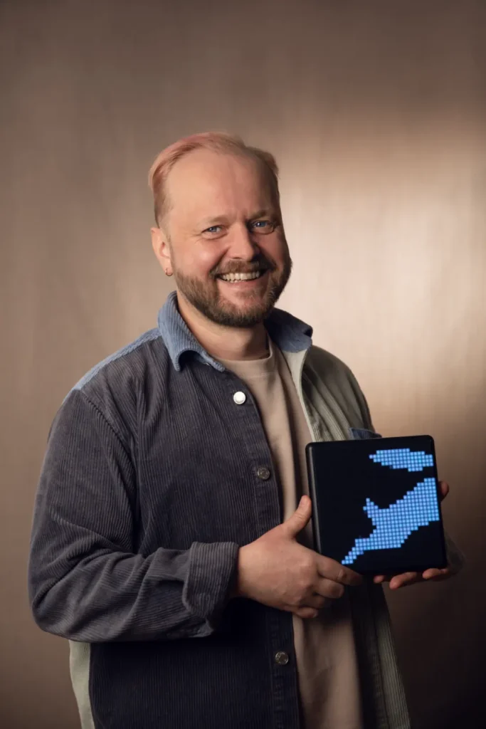 Christoph Ratzenböck der GEO Experte hält ein digitales Schild mit seinem Logo in der Hand und lächelt professionell in die Kamera